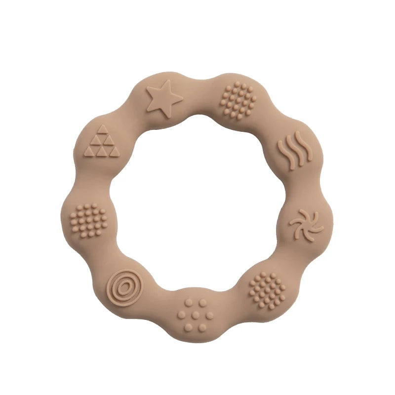 Beige silicone teething ring with a wavy shape featuring various textured patterns, including stars, dots, spirals, and waves, distributed around its circumference.