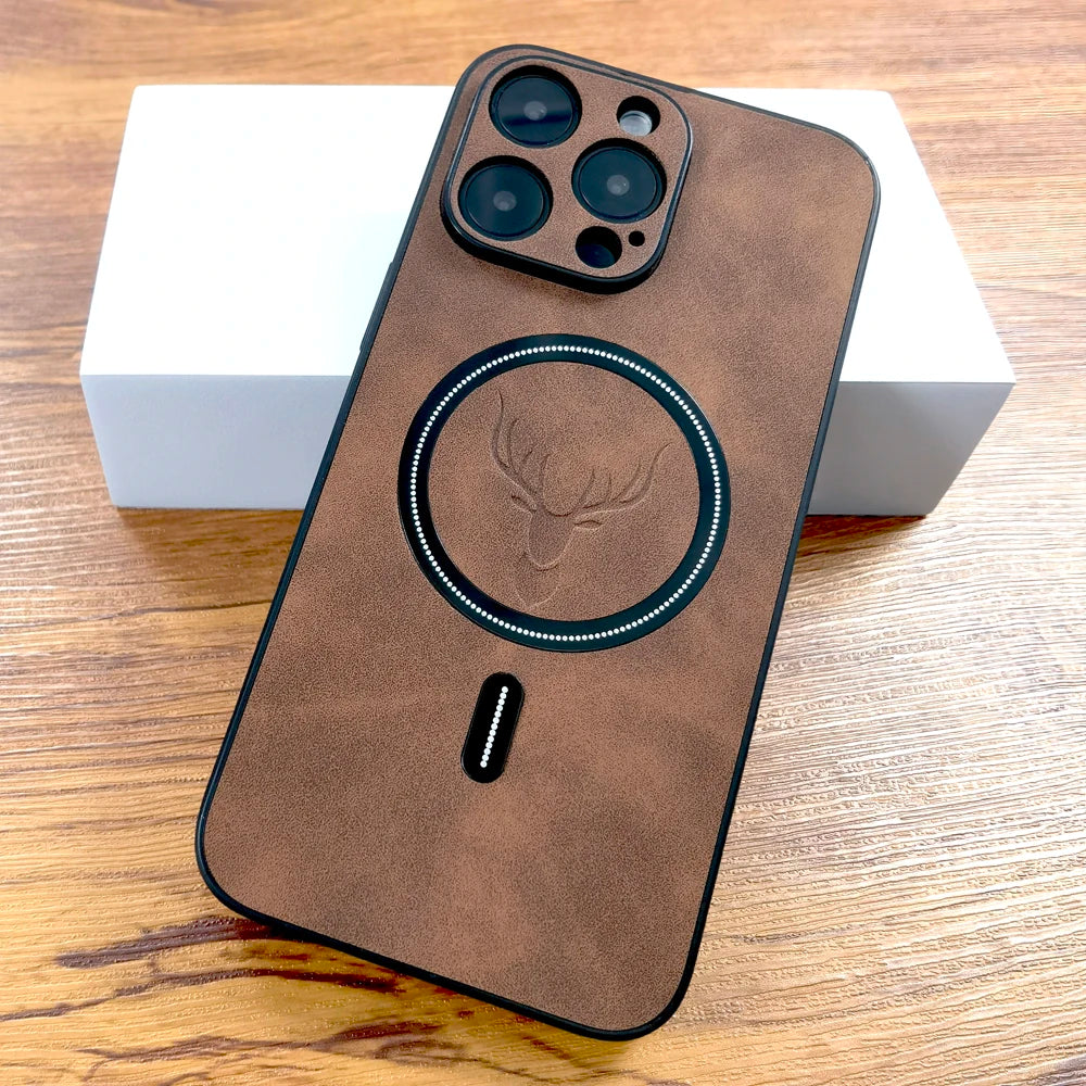 Brown leather phone case with a raised deer design and circular pattern, covering a smartphone with three camera lenses. The phone rests on a white box on a wooden surface.