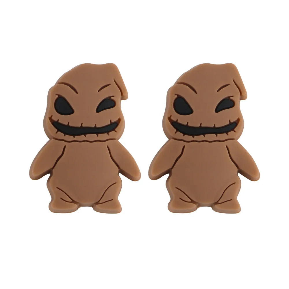 Two brown, cartoon-style figures with stitched mouths and black eyes; they appear identical, side by side, with rounded limbs and pointed head details.
