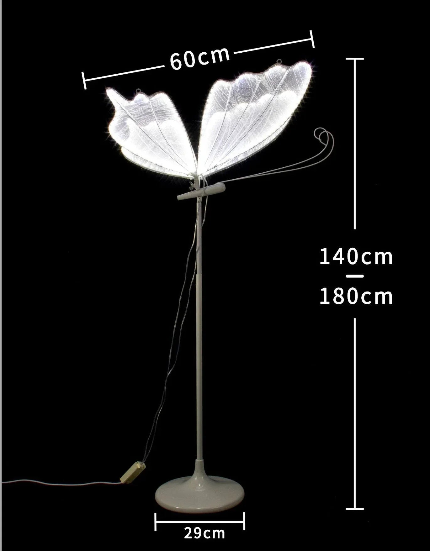 Tall floor lamp with butterfly-shaped wings, measuring 60cm wide and 140-180cm high, on a 29cm circular base. The lamp has a black background and a visible power cord.