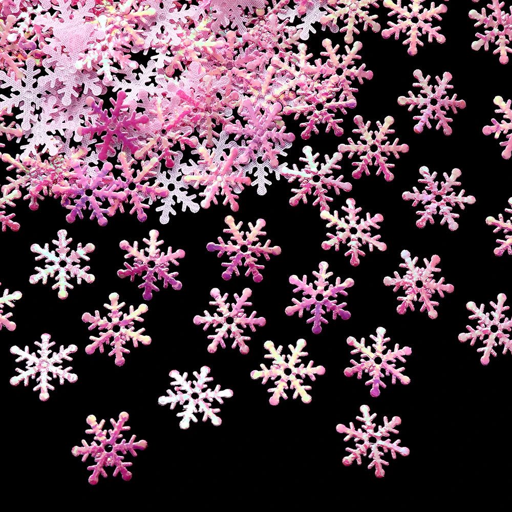 Pink and white glittery snowflake decorations scattered on a black background, creating a festive and contrasting display.
