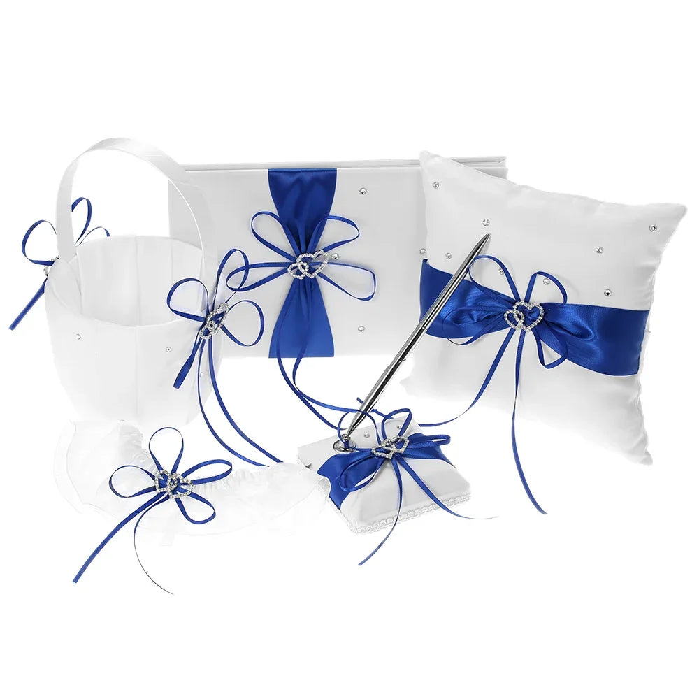 Wedding accessory set with white items accented by blue ribbons and rhinestones, includes a basket, guest book, pillow, garter, and pen with holder.