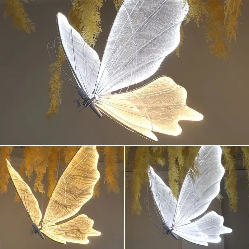 LED butterfly pendant lights with delicate white and amber wings hang against a dark background, surrounded by soft, yellow foliage, creating an ethereal ambiance.