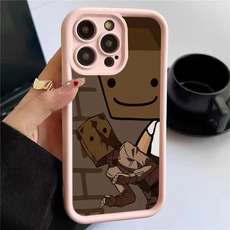Phone case with a pink border featuring a cartoon character with a smiling face and another figure wearing a paper bag over its head. A hand with nail art holds the phone.