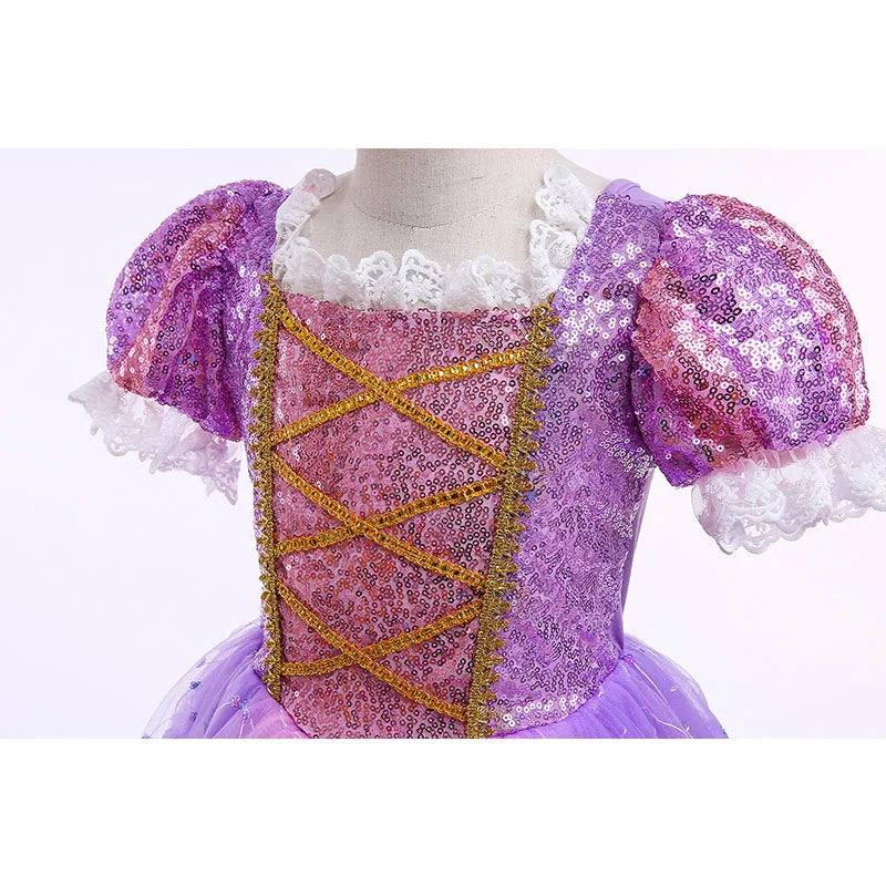 Purple sequin dress with puffed sleeves and gold criss-cross ribbons. White lace trim decorates the neckline. A tutu skirt is visible, adding a whimsical touch.