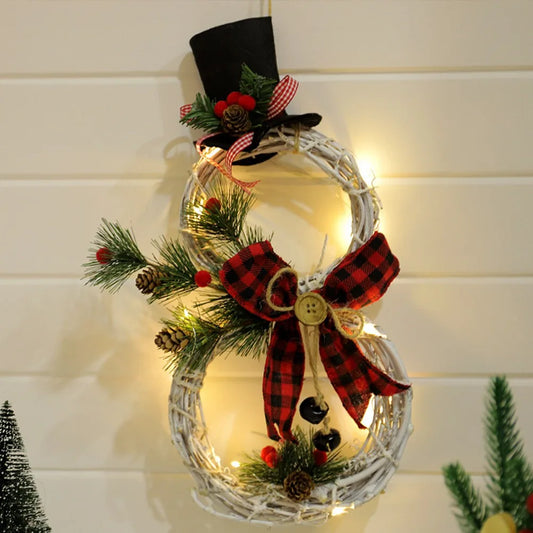 Festive wreath shaped like a snowman with a top hat, plaid bow, and pine accents, adorned with warm white string lights, hanging on a light background.