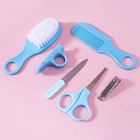 Baby grooming set on a pink background, featuring a blue brush, comb, nail scissors, file, finger brush, and silver nail clipper.
