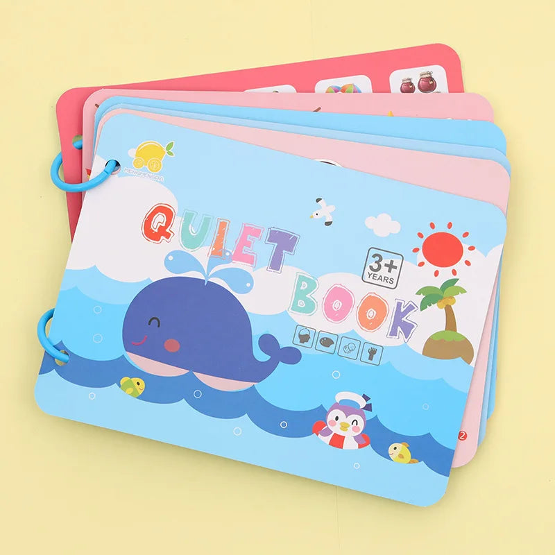 Colorful children's quiet book for ages 3+, with a smiling blue whale, playful penguin, and small chick on a sunny ocean scene. Pages are held together with blue rings.