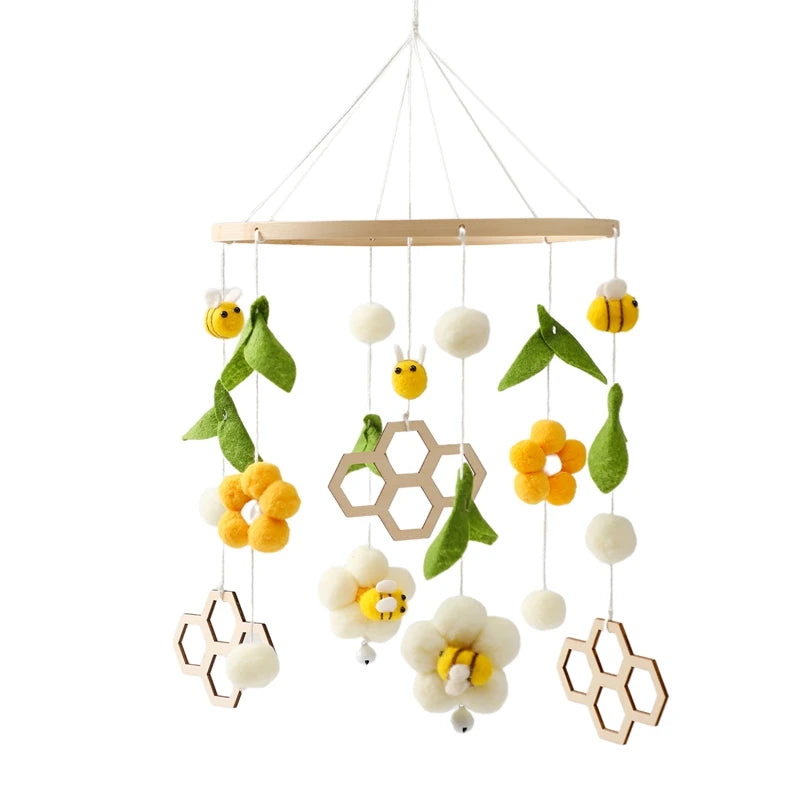 Hanging mobile features bees, flowers, green leaves, and hexagonal shapes made from felt and wood, suspended from a circular frame.