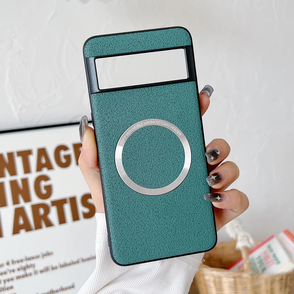 A hand with painted nails holds a teal-colored smartphone case featuring a circular metallic magnetic card holder. A white wall and framed text are visible in the background.