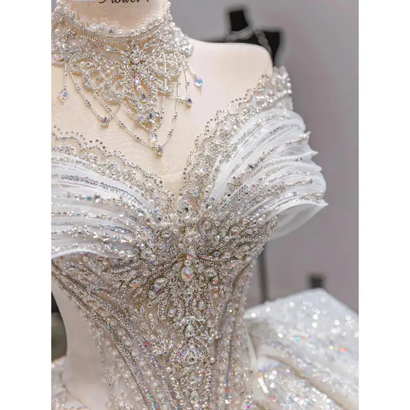 Intricately beaded white gown on a mannequin, featuring a heart-shaped neckline with sparkling crystals and detailed embellishments.