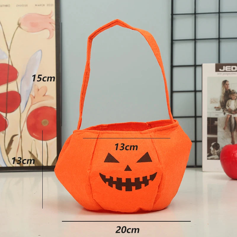 Orange felt pumpkin bag with a black jack-o'-lantern face, featuring a handle and dimensions: 20cm wide, 13cm tall, and 15cm deep. Background includes wall art and decor.