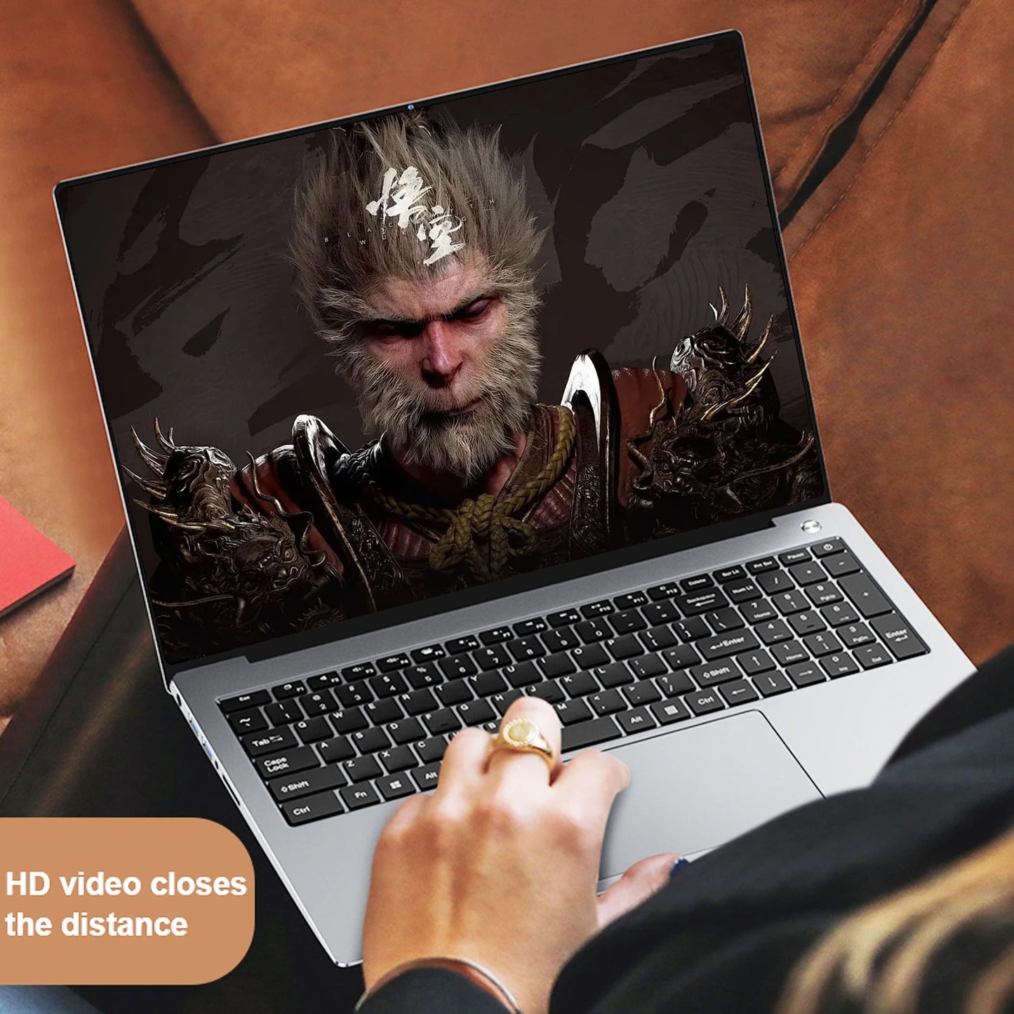 A person with a gold ring uses a laptop showing a detailed video of a fantastical, armored character with animal features. Text overlay reads, "HD video closes the distance."