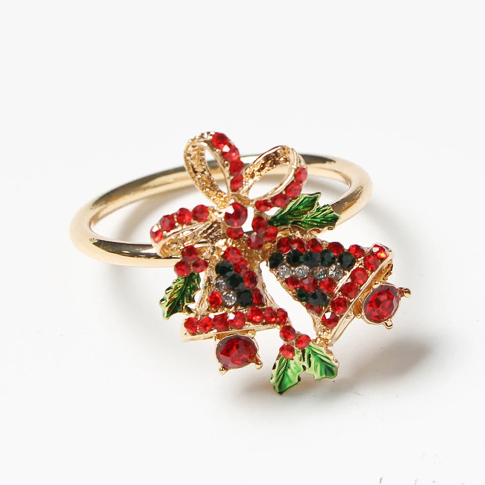 Gold ring with a decorative setting of red, green, and black stones forming a festive bow and bell design, accented with sparkling details.