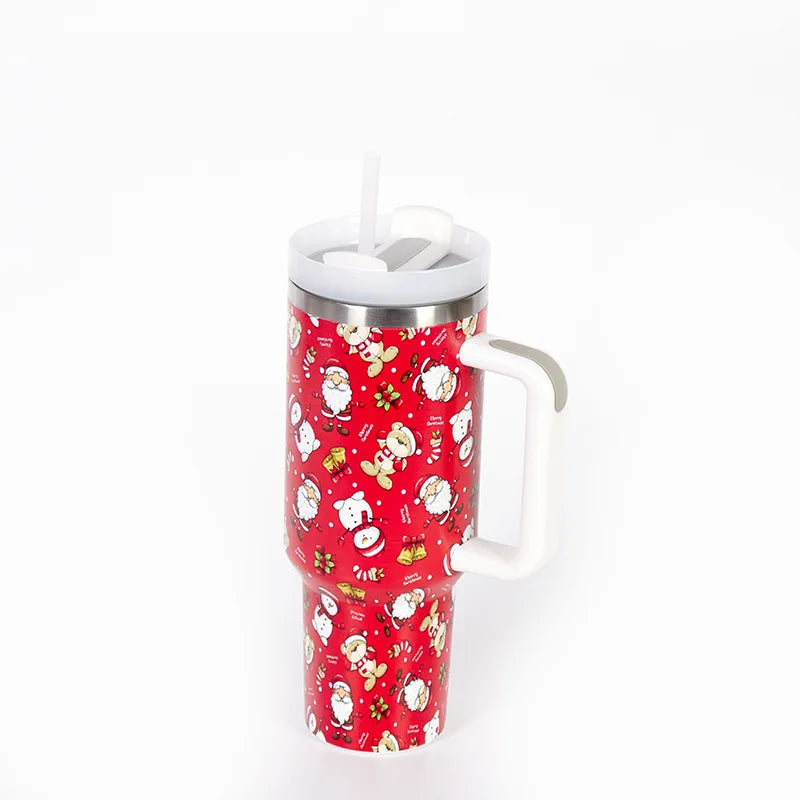 Red tumbler with Christmas-themed graphics, including Santas and reindeer, featuring a white handle and lid with a straw, isolated on a white background.