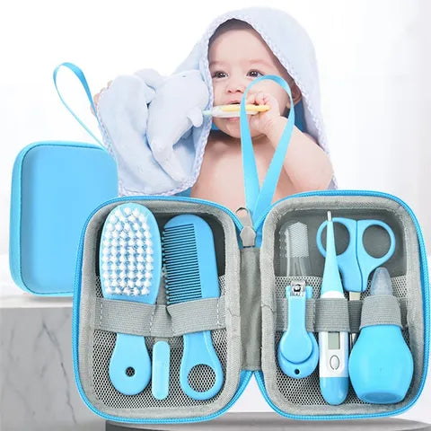A baby wrapped in a blue towel with a dolphin design uses a toothbrush. In the foreground is an open blue baby care kit, including a brush, comb, scissors, nail clippers, and more.