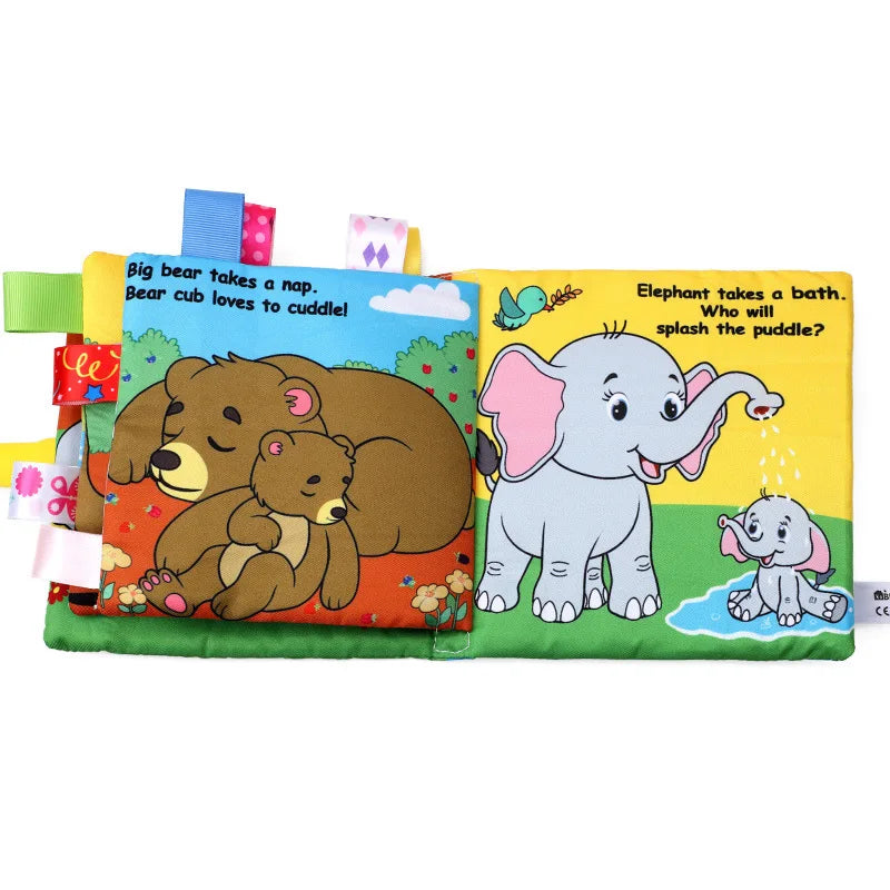 Soft baby book with colorful illustrated pages. Left page: bears napping and cuddling. Right page: elephants playing with water. Tabs with ribbons border the book.