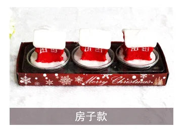 Three decorative red and white Christmas-themed items resembling small houses, set in a festive box with "Merry Christmas" and snowflake patterns.