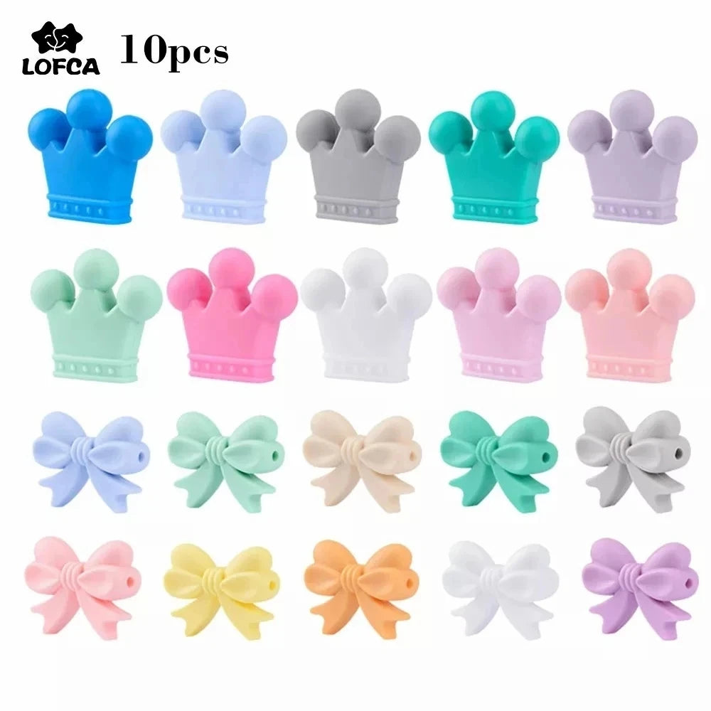 Colorful silicone beads shaped like crowns and bows are arranged in rows. Each row features various pastel shades including blue, green, pink, white, and more.