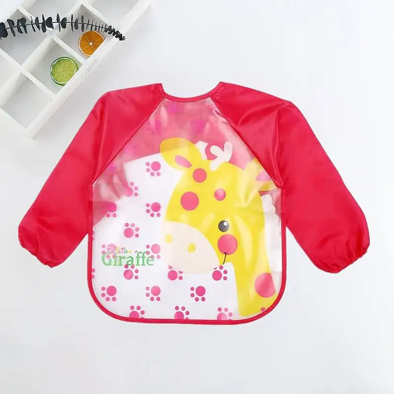 Bright red children's apron with long sleeves featuring a cheerful yellow giraffe and pink paw prints on the front. Text reads "Giraffe." Displayed on a white background.