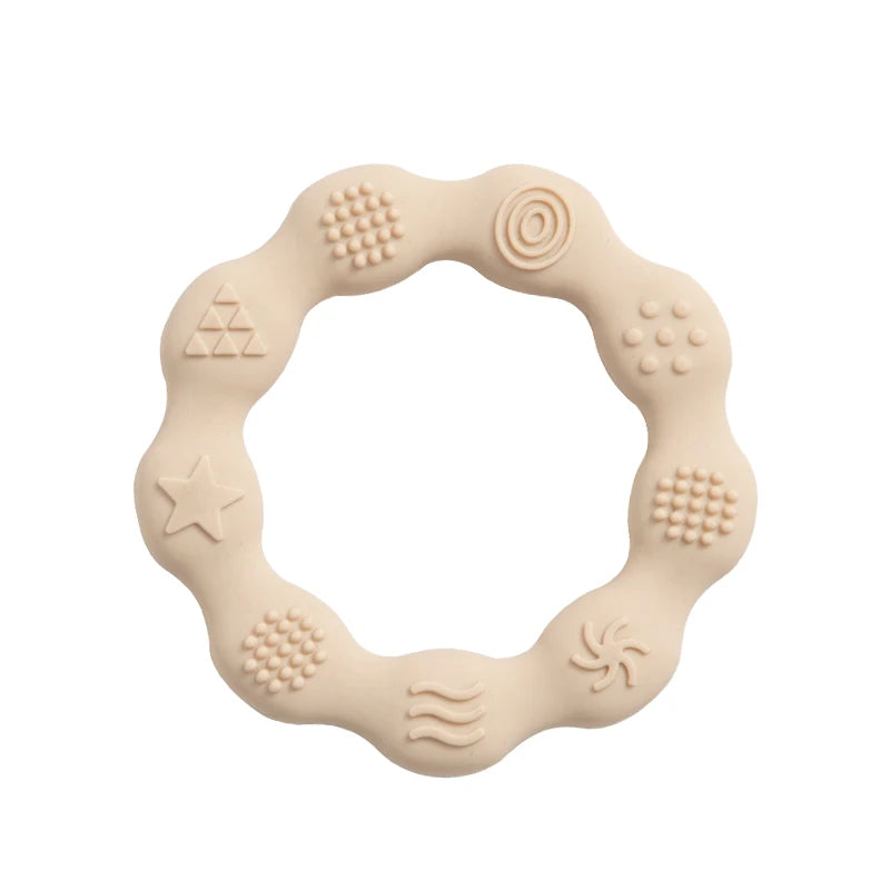 A beige silicone teething ring with a wavy edge features various raised patterns, including stars, circles, and spirals, designed to provide tactile stimulation for infants.