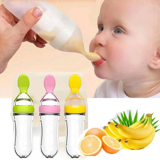 A baby is being fed from a silicone squeeze feeder next to three colorful feeders. In the foreground, bananas and orange slices are displayed, suggesting flavor options.