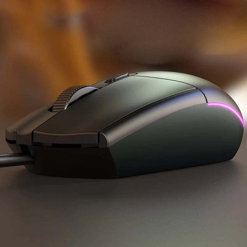 A sleek black computer mouse with a scroll wheel is illuminated by a pink LED light on its side, resting on a smooth surface with a warm, blurred background.