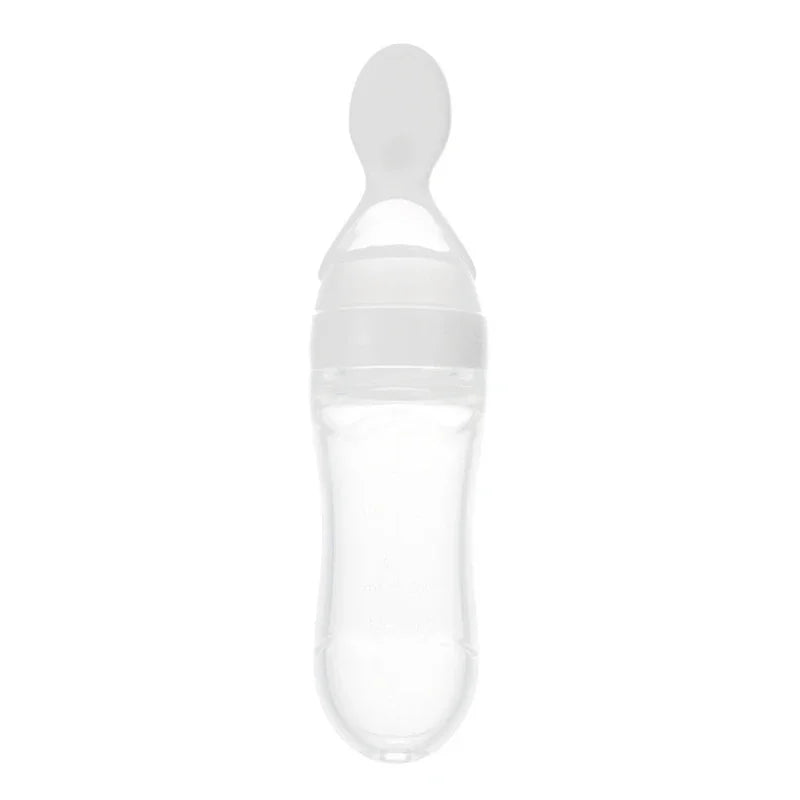 Clear silicone baby food bottle with an attached feeding spoon. The bottle has a rounded base, tapering towards the top, and a wide opening for easy filling and cleaning.