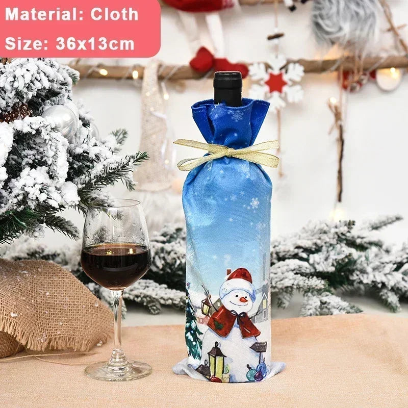 A wine bottle wrapped in a blue cloth with a snowman design sits next to a glass of red wine. Snow-covered Christmas decorations are in the background.