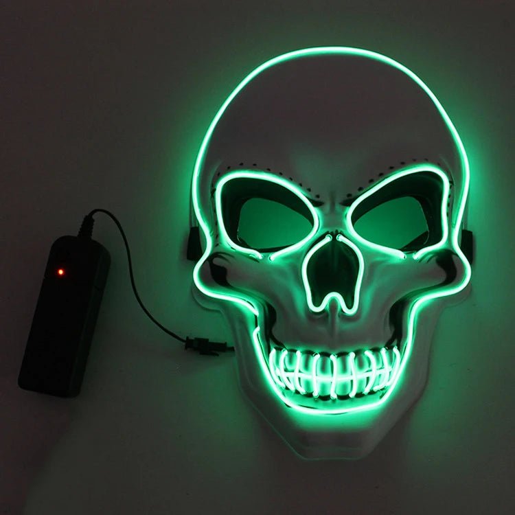 Glowing skull mask with neon green outline and black eye sockets, connected to a small black power pack, displayed against a dark background.
