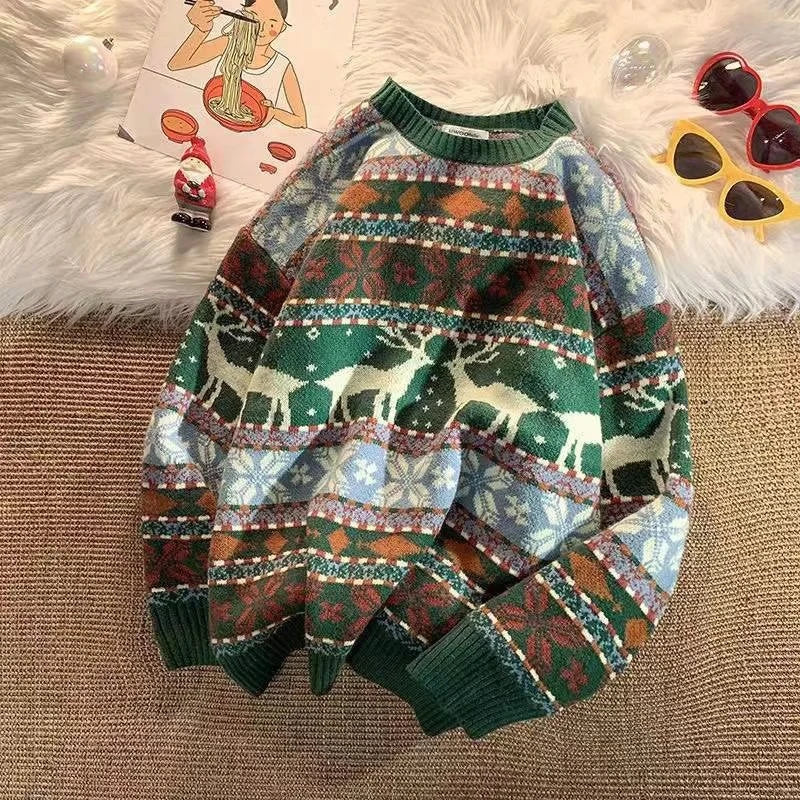 A festive sweater with a green collar and cuffs, featuring reindeer, snowflakes, and floral patterns in green, brown, and blue, surrounded by sunglasses, a magazine, and a Santa figurine.