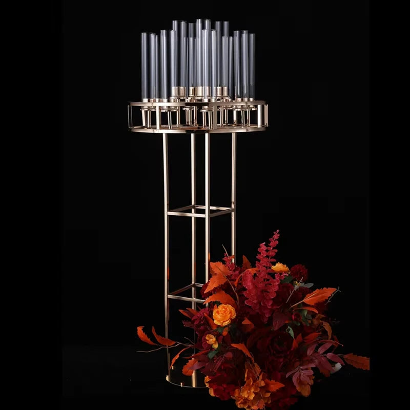 Elegant gold candelabra with tall glass encasements displayed on a black background, accompanied by a vibrant bouquet of autumn flowers in shades of red, orange, and yellow.