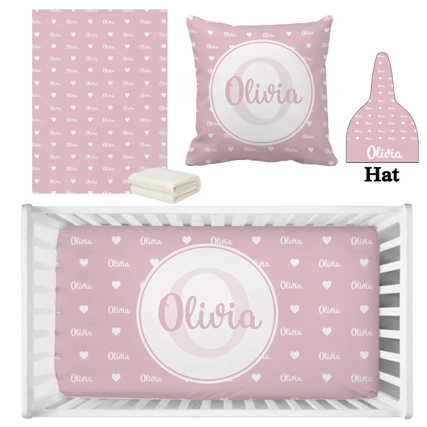 Pink nursery set with a blanket, pillow, hat, and crib sheet featuring white hearts and personalized name "Olivia" in cursive. Sheets beside folded white fabric.