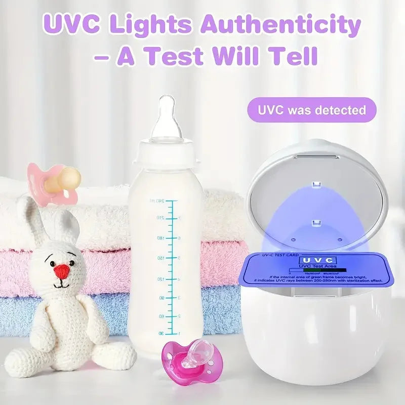 UV sterilizer with open lid showing blue light on test card, surrounded by baby essentials: a bottle, pacifiers, towel stack, and a plush bunny. Text reads "UVC Lights Authenticity."