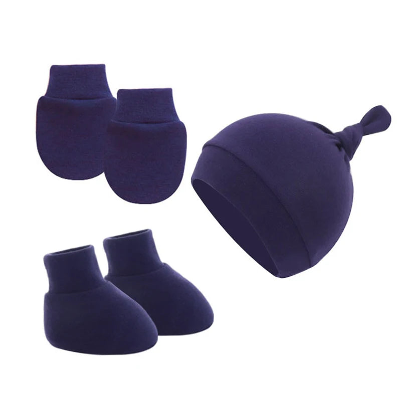 Navy blue baby set including mittens, booties, and a knotted hat, displayed against a white background.