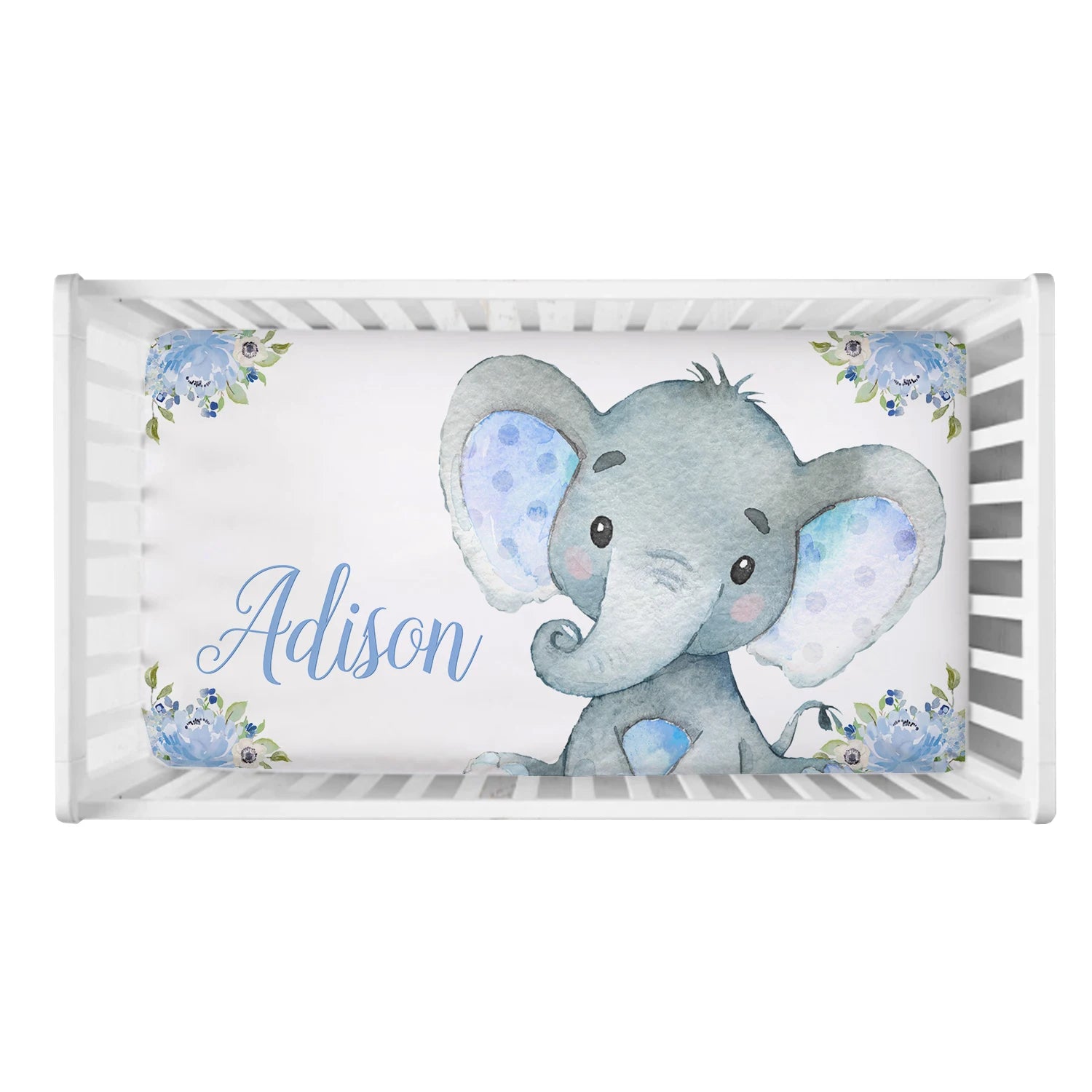 Crib with white slats featuring a cute watercolor elephant on the mattress, surrounded by blue and purple flowers. The name "Adison" is written in elegant blue script.