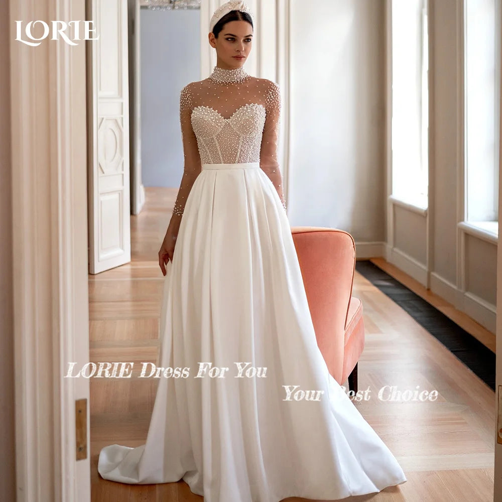 Bride in an elegant wedding dress with a beaded sheer top and full skirt, standing by a coral chair in a bright, classic room. Text on image says "LORIE Dress For You."