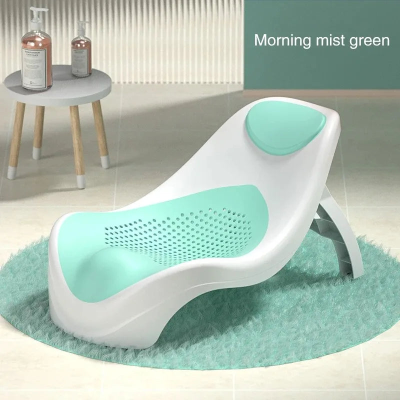 Modern, ergonomic baby bath seat in white and mint green with perforated design on a round, fluffy rug. Nearby, a side table holds two pump bottles. Titled "Morning mist green."