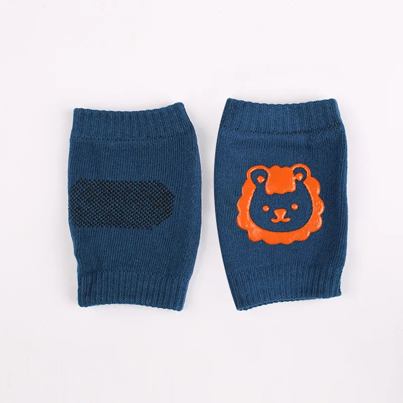 Two blue baby knee pads on a white background. One has a black non-slip pad, and the other features an orange lion design.