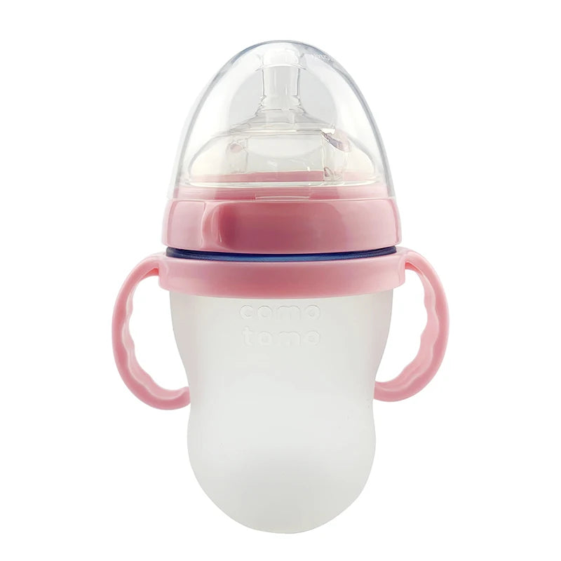 Pink-handled baby bottle with a silicone body and transparent lid. It has a soft, nipple-like spout designed for easy grip.