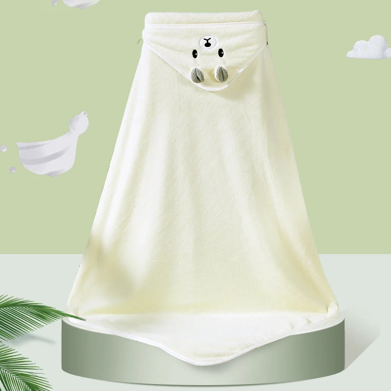 Ivory-colored, hooded baby towel with a cute animal face and ears on the hood, displayed on a green pedestal with a pale green background featuring white cartoon clouds.