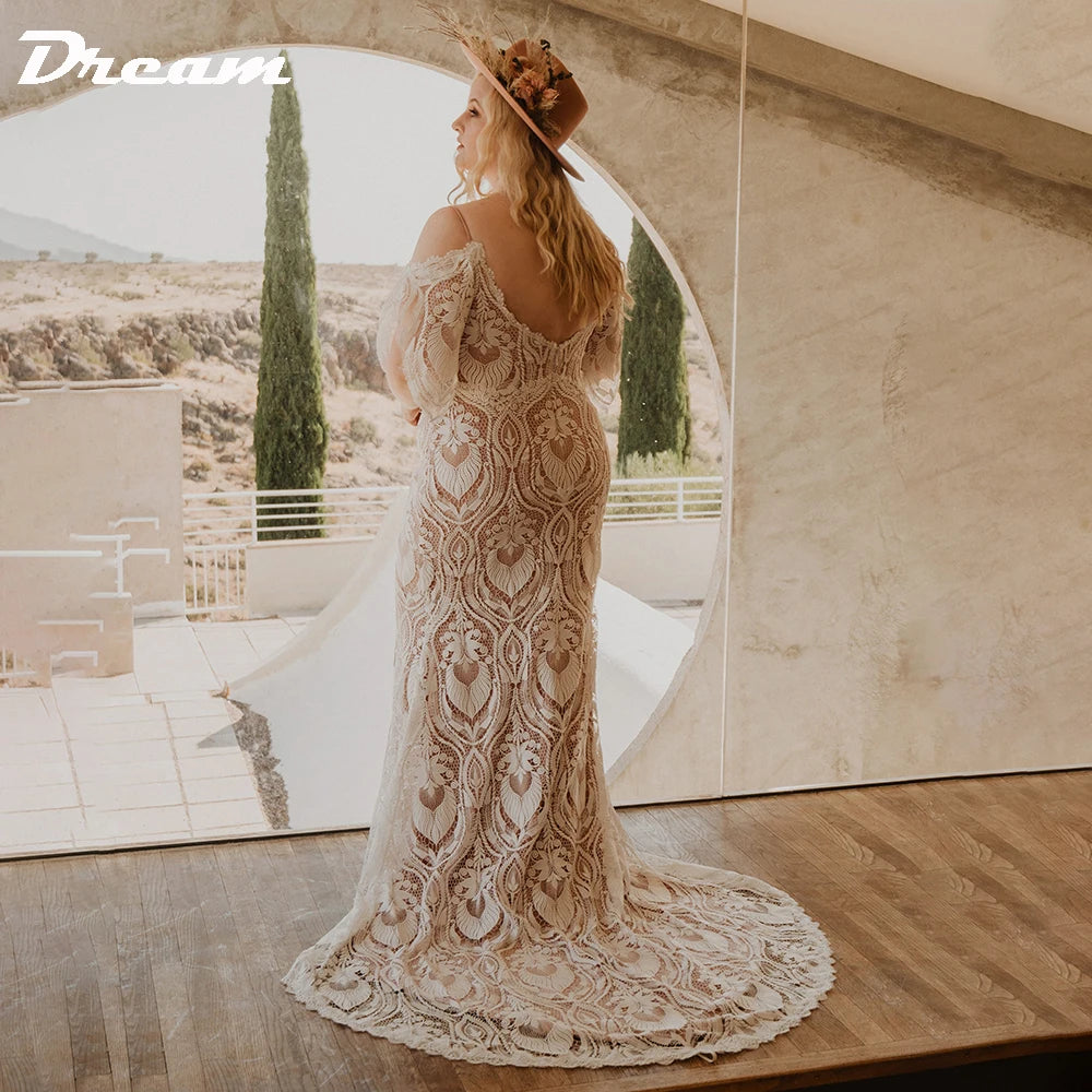 A woman in a lace wedding gown and wide-brimmed hat stands by a large round window, gazing outdoors. The setting is bright, with a scenic view of trees and hills.