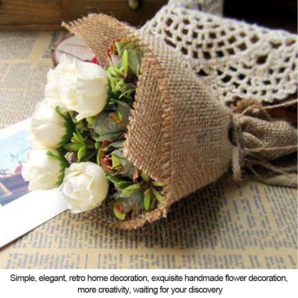 A burlap-wrapped bouquet of white roses and greenery rests on a newspaper, with a crocheted fabric nearby, creating a vintage, rustic decor scene.