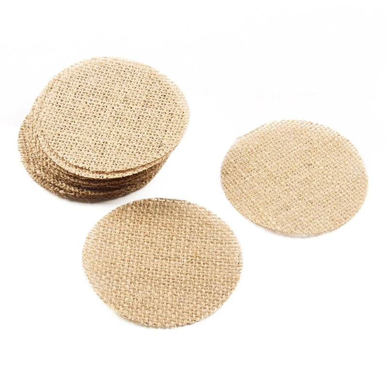 A stack of round beige burlap coasters on a white background, with a few scattered individually. The coasters have a rustic, woven texture.