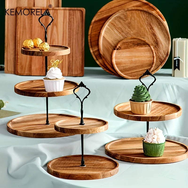 Wooden tiered trays display assorted cupcakes and chocolates, set on a table with a pale cloth. In the background are wooden cutting boards and a book.