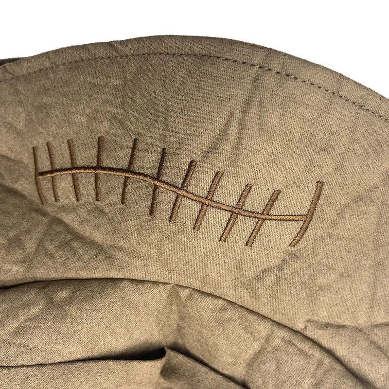 Close-up of a light brown fabric with a stitched pattern resembling a curved line, crossed by vertical stitches, creating a railroad track design.