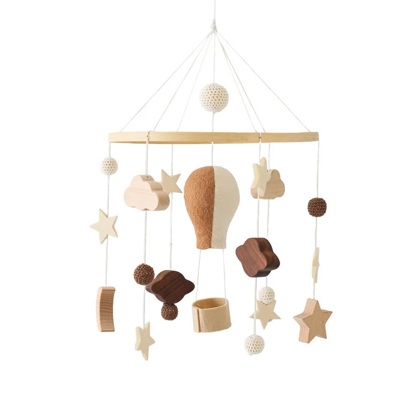 Wooden baby mobile featuring a hot air balloon, stars, clouds, and textured balls hanging from a circular frame. Natural tones provide a minimalist, calming aesthetic.