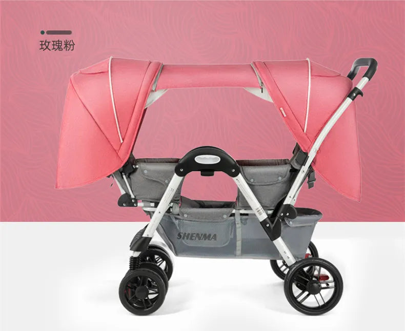 Pink twin baby stroller with canopies, black handles, and four wheels. The background is rosy pink with a subtle pattern. The word "SHENMA" is visible on the storage basket.