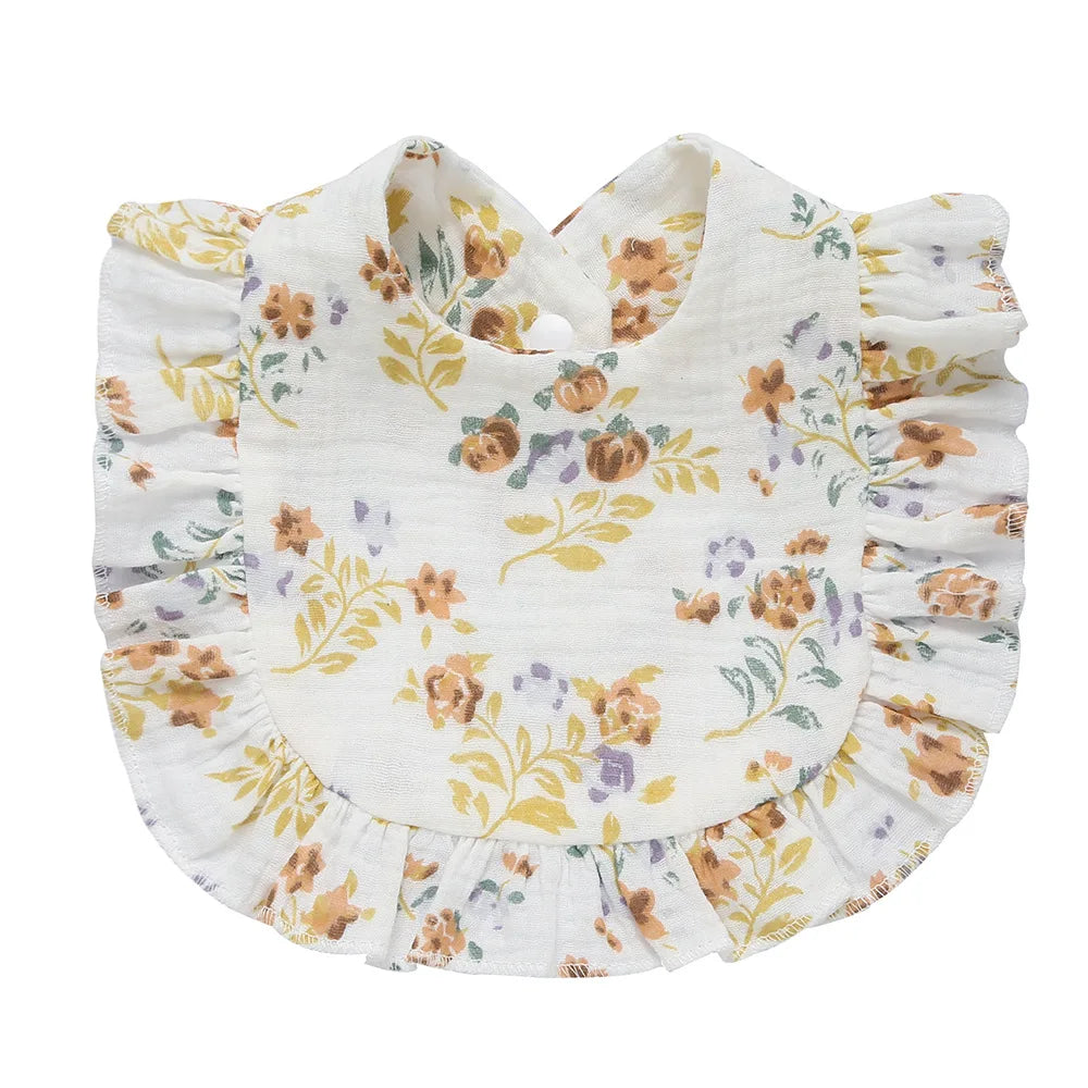 A white bib with ruffled edges featuring a floral pattern in yellow, orange, and purple hues.