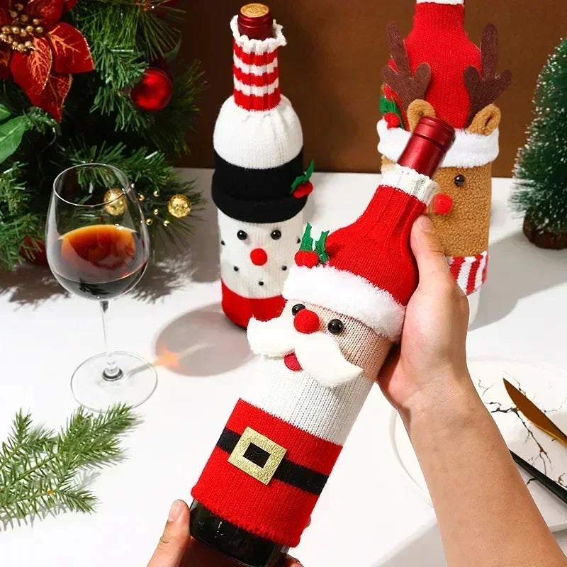 Festive wine bottles dressed in knit covers resembling Santa, a snowman, and a reindeer. A glass of red wine and Christmas decorations are in the background.